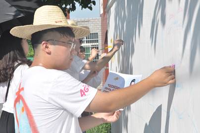 墙绘中，志愿者们顶着烈日画画